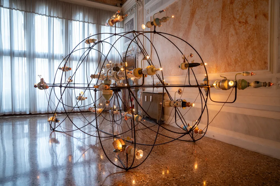 A large spherical installation by Torlarp Larpjaroensook fills an ornate room with metal structures, cables and glowing light elements.