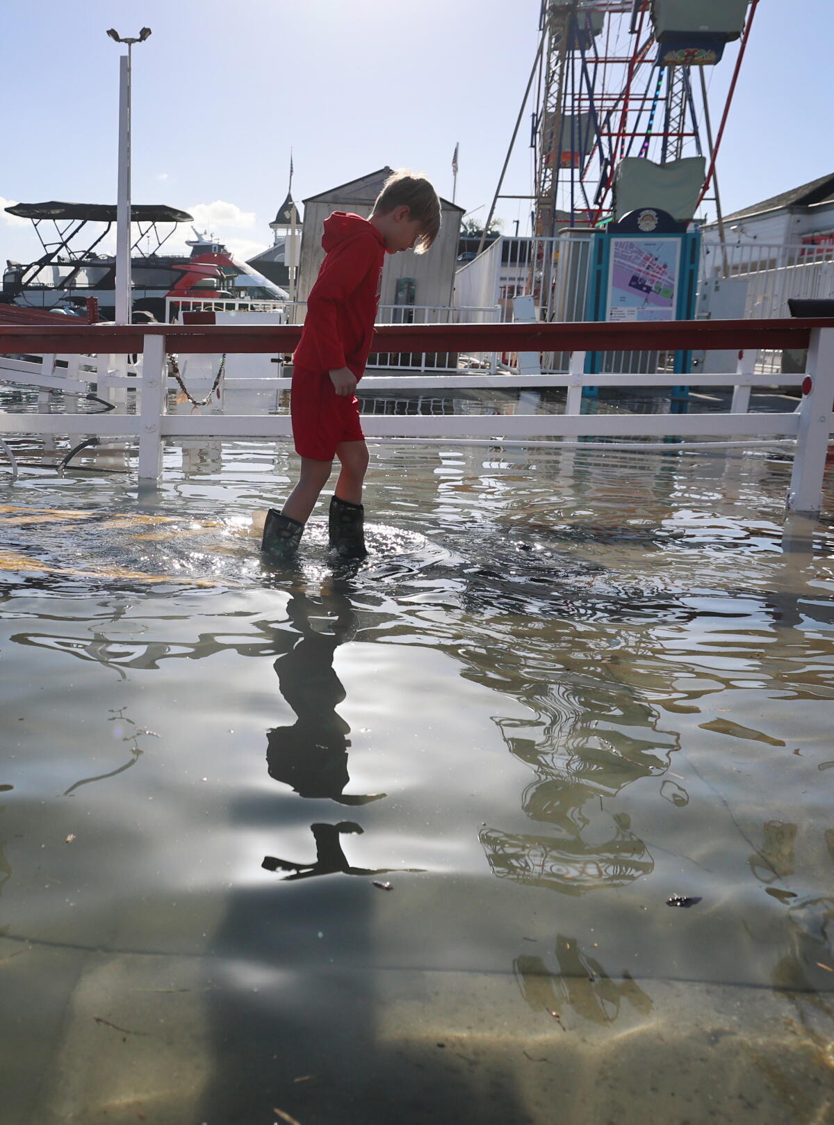 A young boy disembarks from the Balboa Island Ferry and wades through floodwaters on the Newport Beach Peninsula.