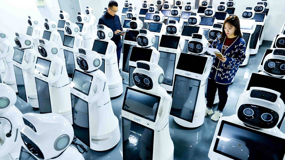 Workers with a robot assembly line in a factory.