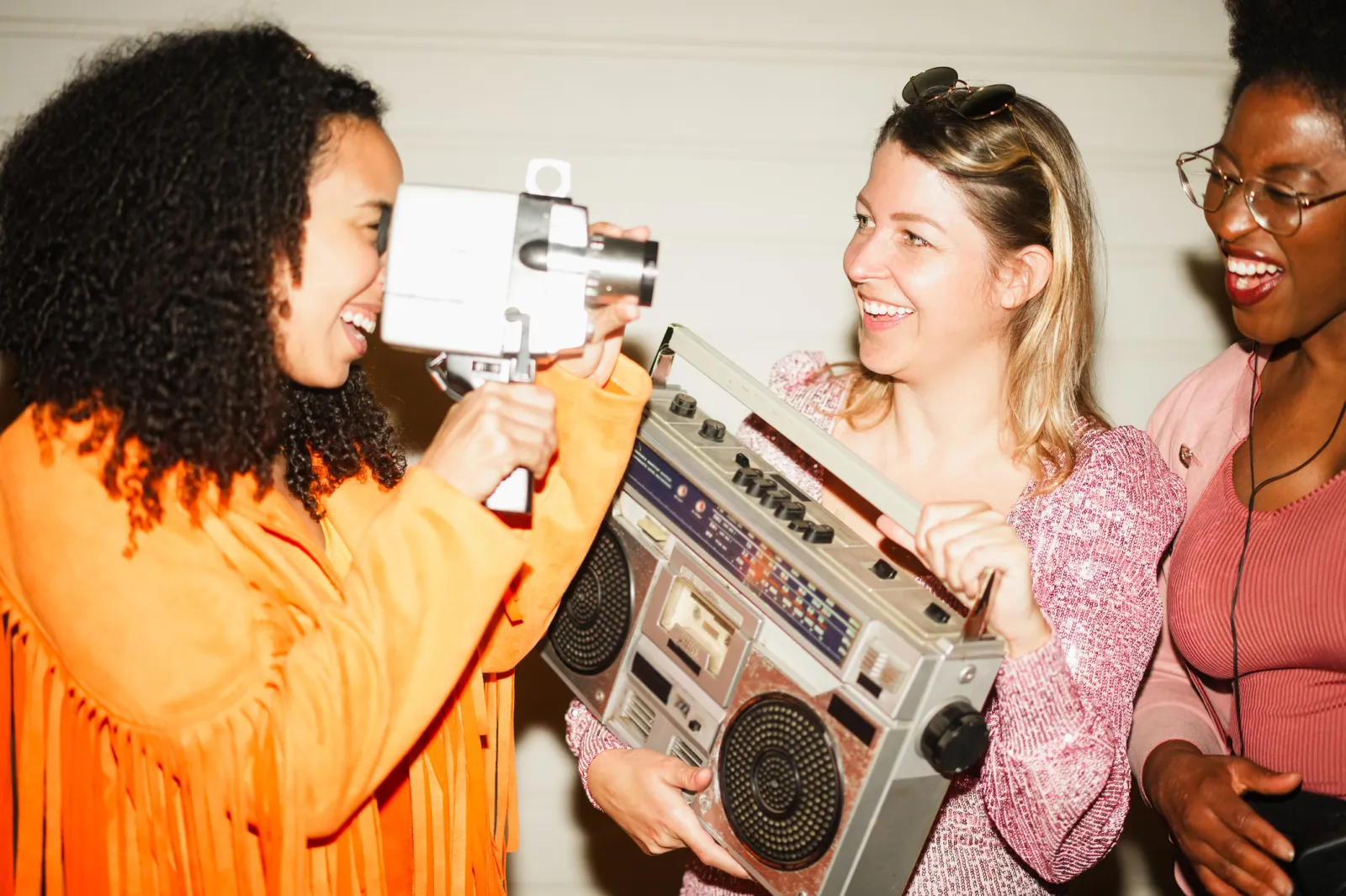 A woman holding a vintage camera, while another holds a retro music player box.