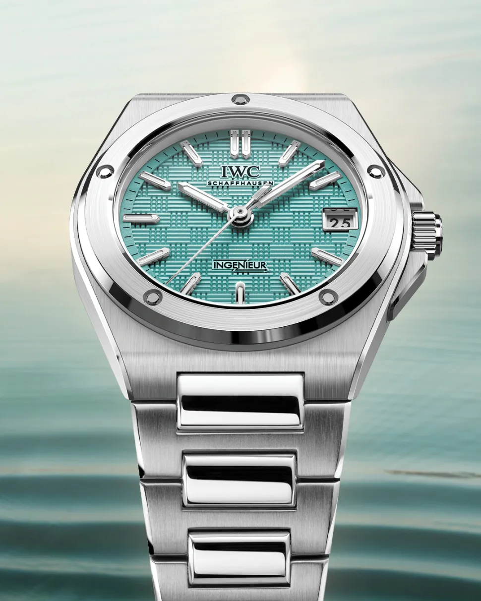 The IWC Ingenieur Automatic 35 watch features a textured turquoise dial, stainless steel case and integrated bracelet against a softly blurred pale background.