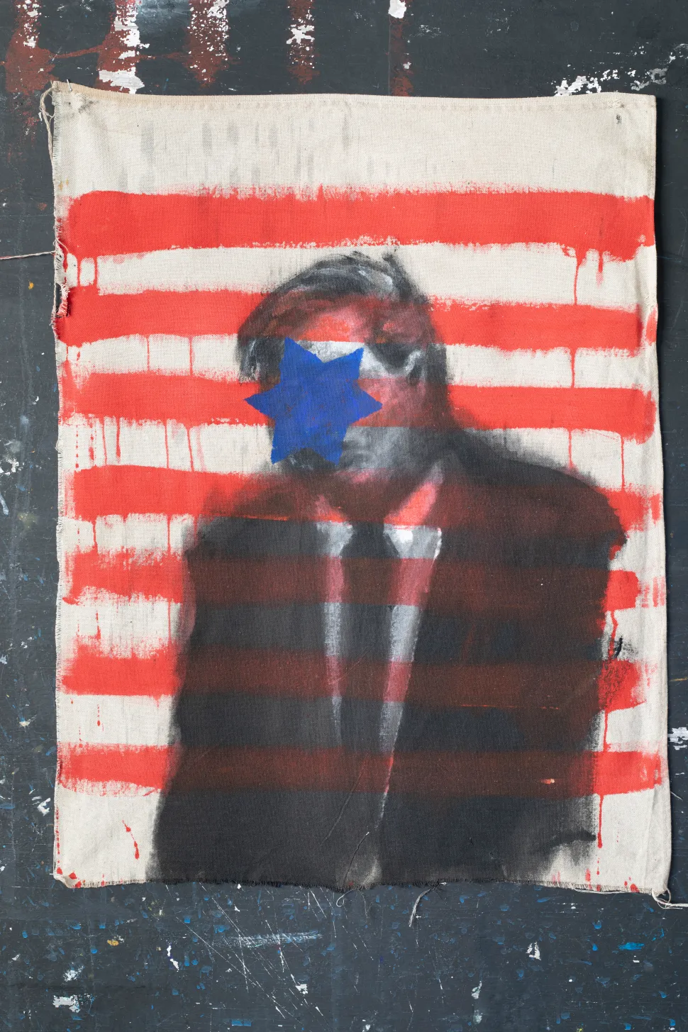 The portrait of a man in a suit, his face covered with red horizontal stripes and a blue star, is reminiscent of the visual language of the flag.